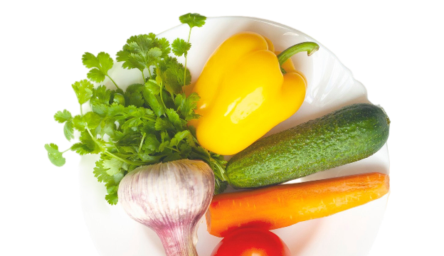Yellow pepper cucumber carrot garlic herbs and tomato on a plate