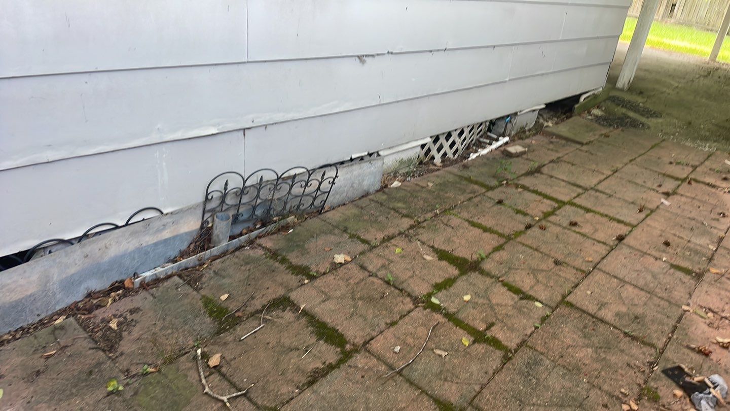 A metal grate on the side of a house for foundation repair.