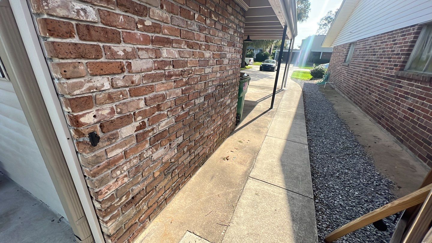 A brick wall next to a sidewalk with a door, indicating home elevation.
