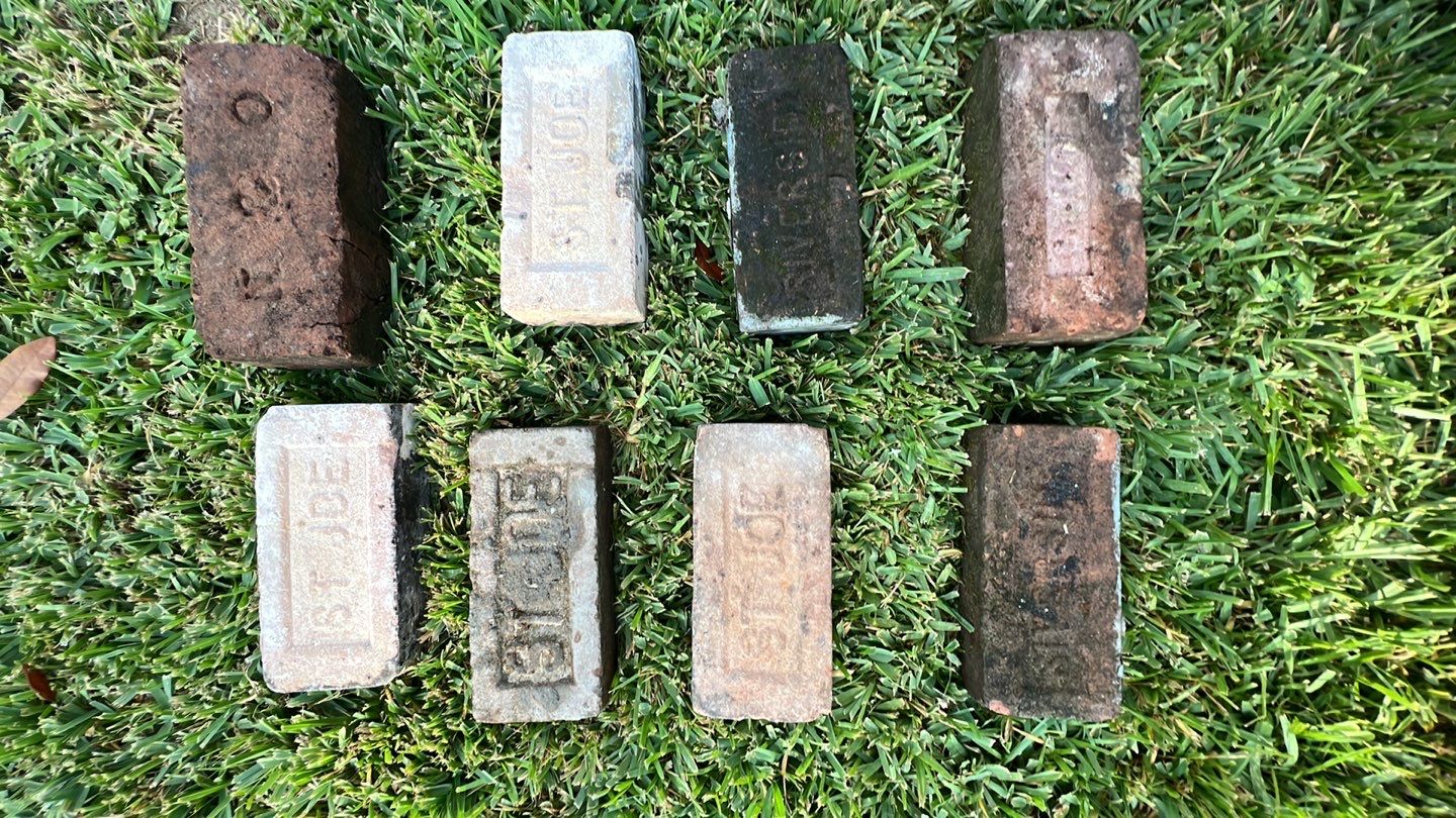 Old bricks laying on the grass, potentially needing foundation repair.