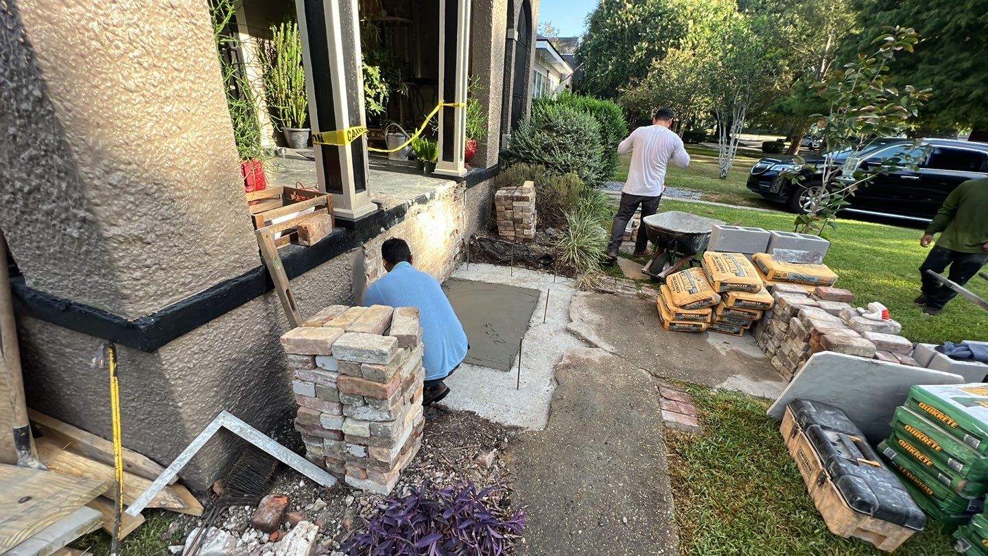 A group of men are working on house foundation repair in front of a brick wall.
