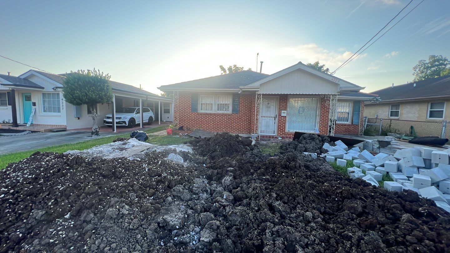 A house undergoing foundation repair with a pile of dirt in front of it.