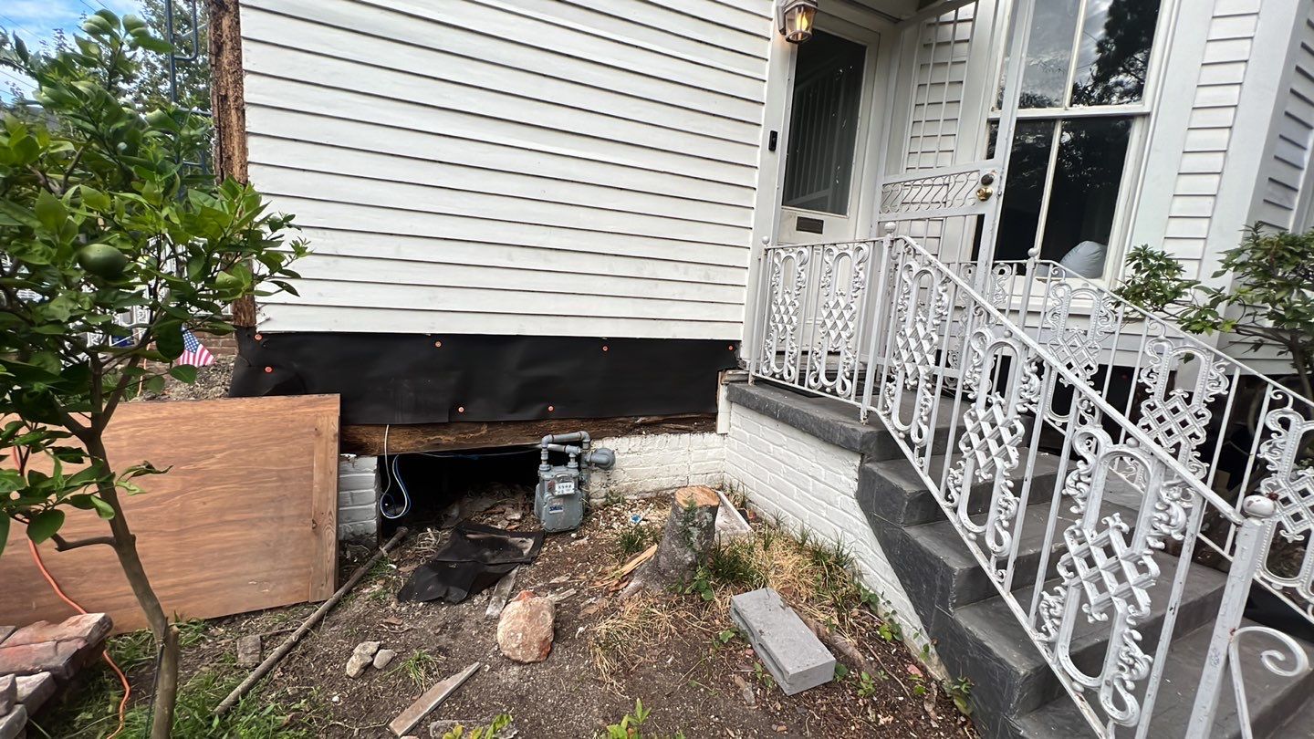 A house with a stairway and a metal railing undergoing foundation repair.