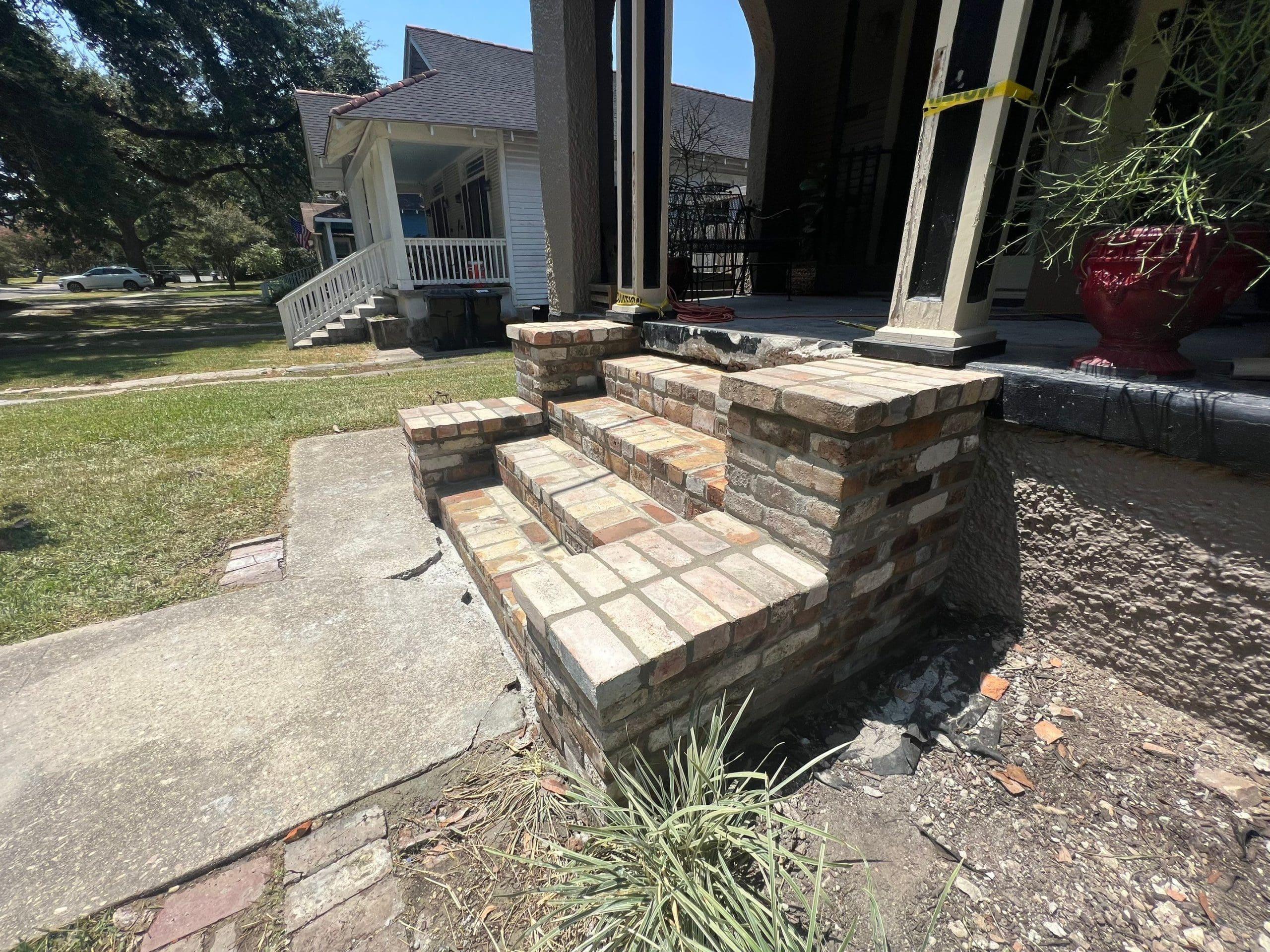 A house with brick steps and foundation repair in front of it.