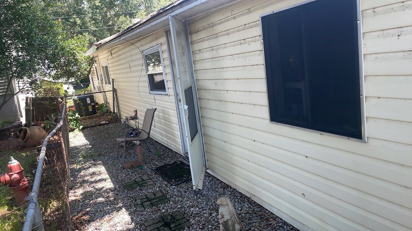 A white house with a fence in need of foundation repair in a small backyard.