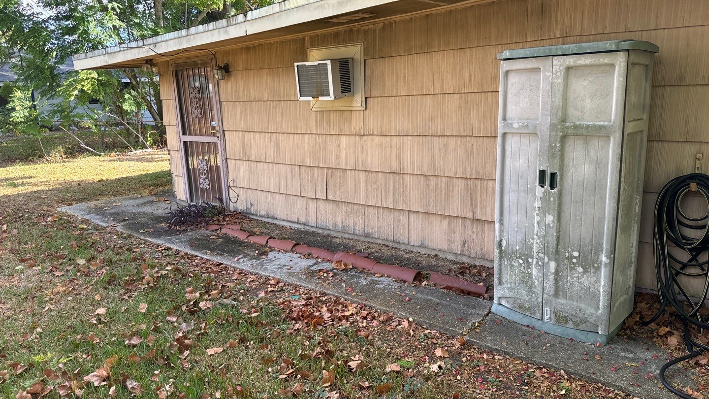 A wooden cabinet sits on the side of a house.
