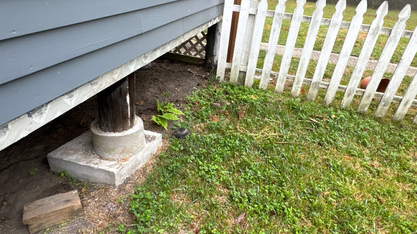 A white picket is next to a gray house.